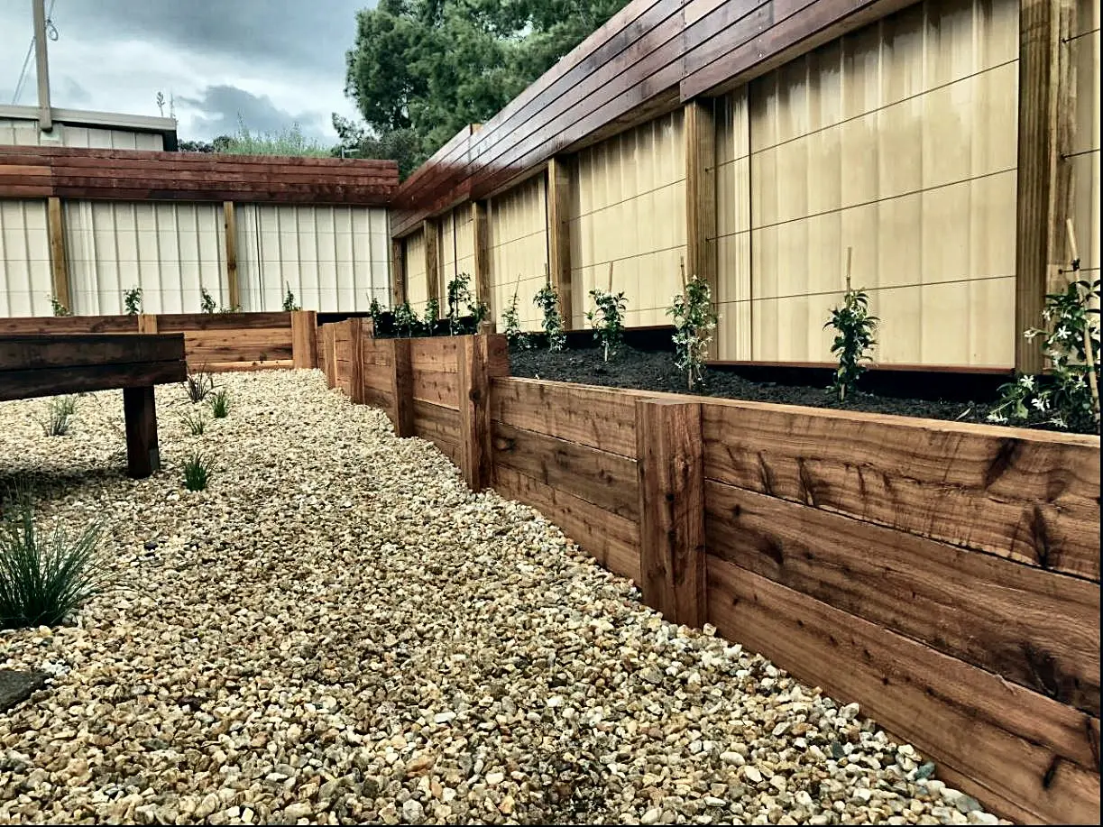 Pressure-treated timber retaining wall with a gravel bed